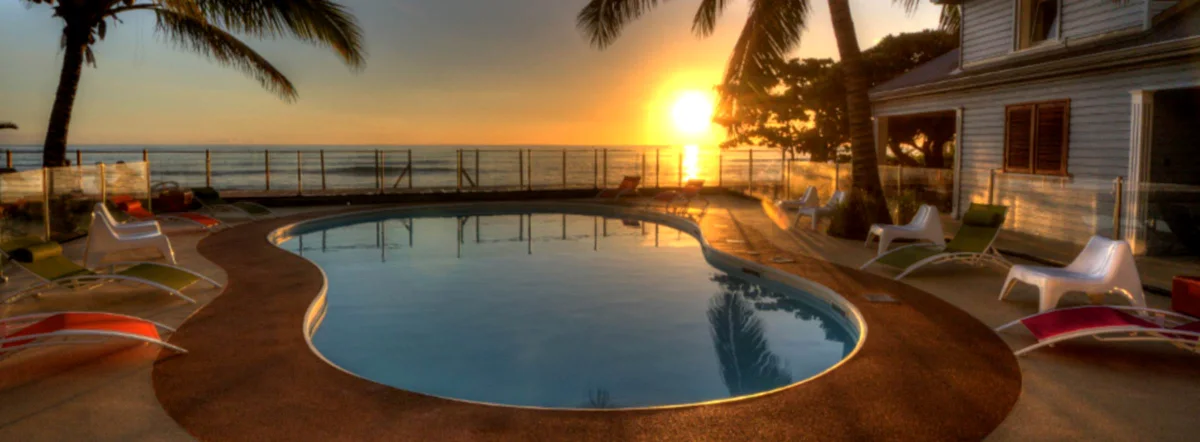 Le soleil se couche sur l'océan, derrière la piscine