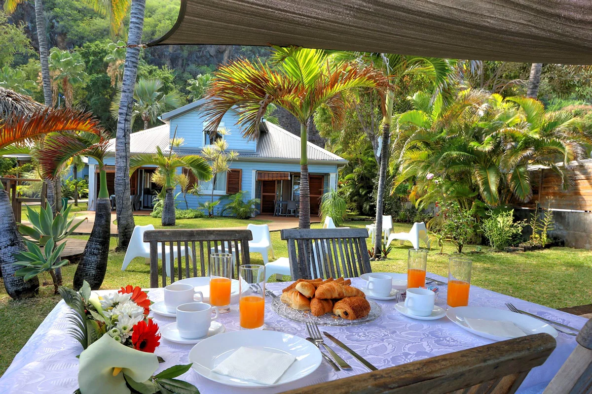 Un petit déjeuner sur une table du jardin, face à une villa