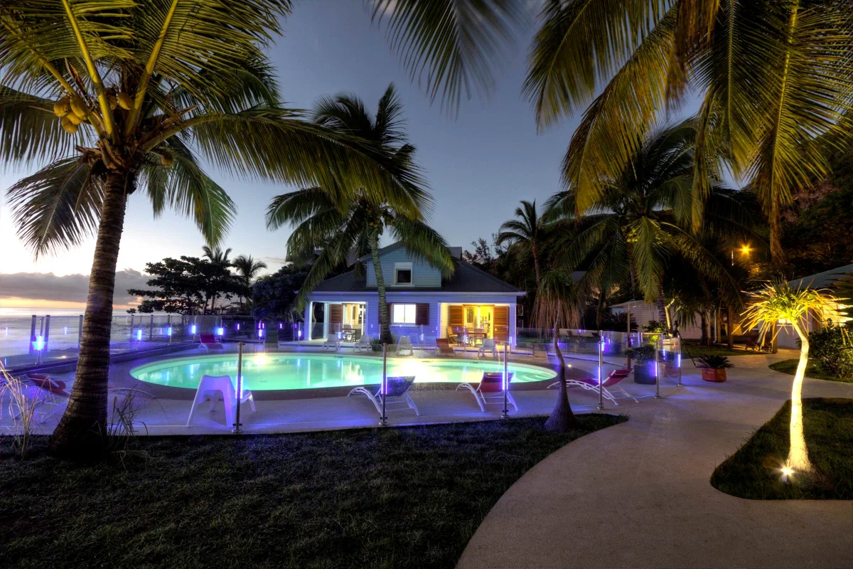 La piscine éclairée le soir, les villas et les cocotiers
