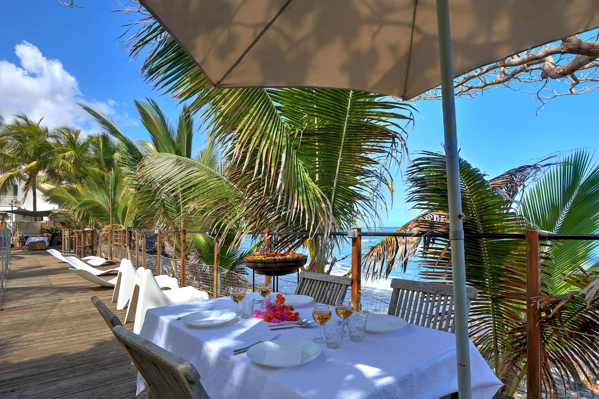 Une table dressée au bord de la mer, avec le barbecue à côté