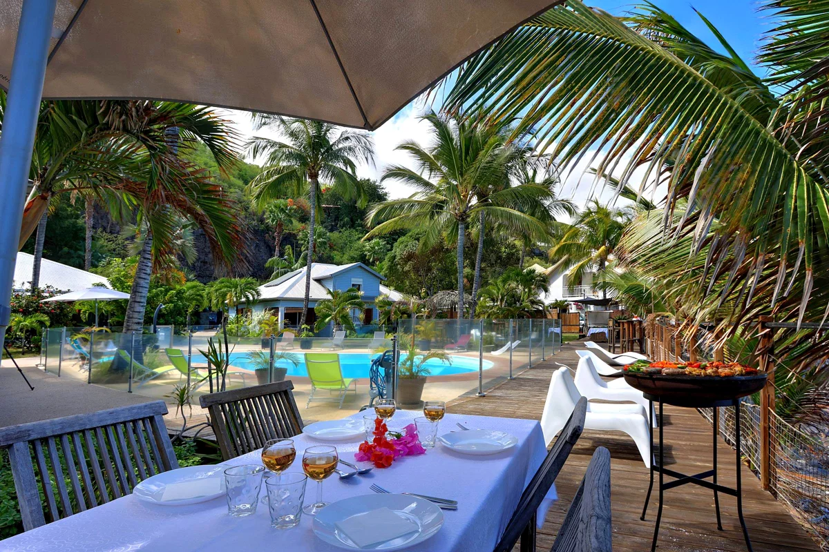 Les tables dressées sous les cocotiers, à côté de la piscine