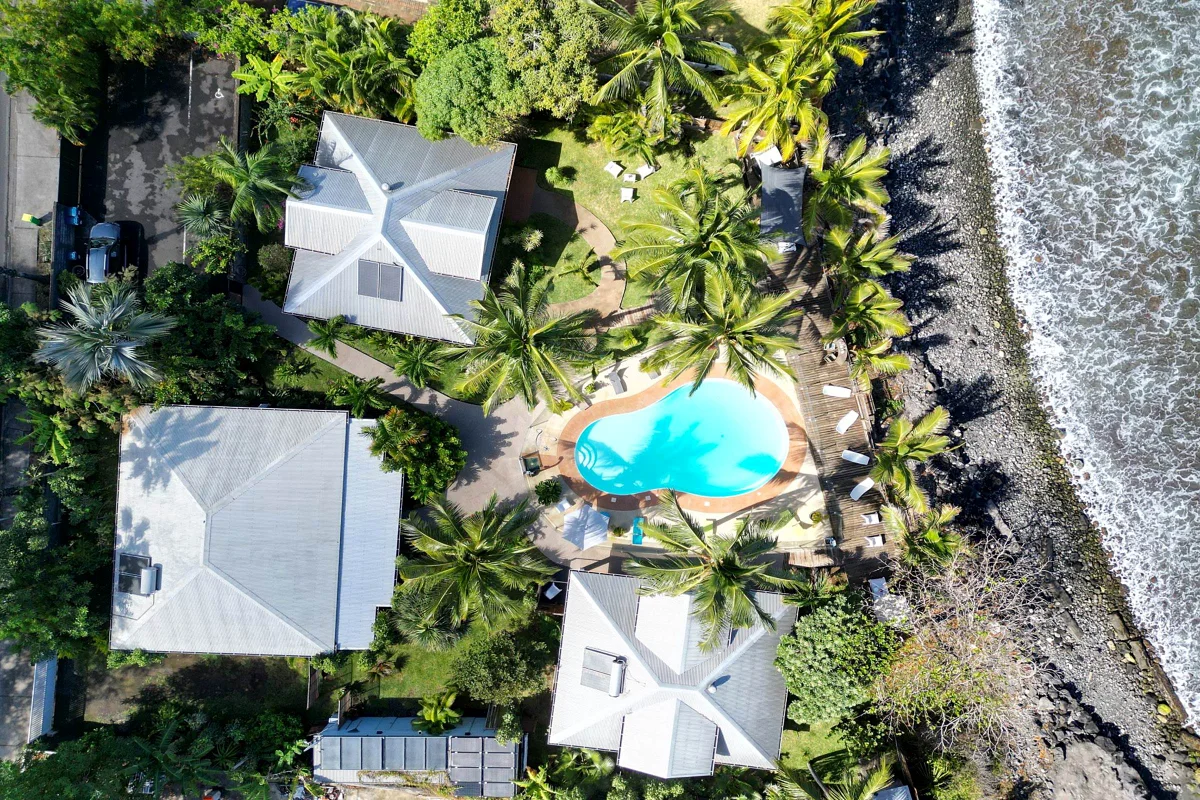 Les villas, la piscine et les cocotiers vus du ciel, au bord de l'océan